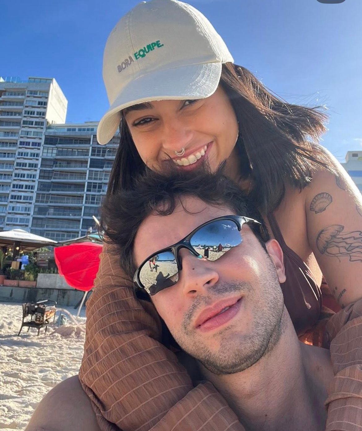 Casal na praia, ela usando boné Bora Equipe branco